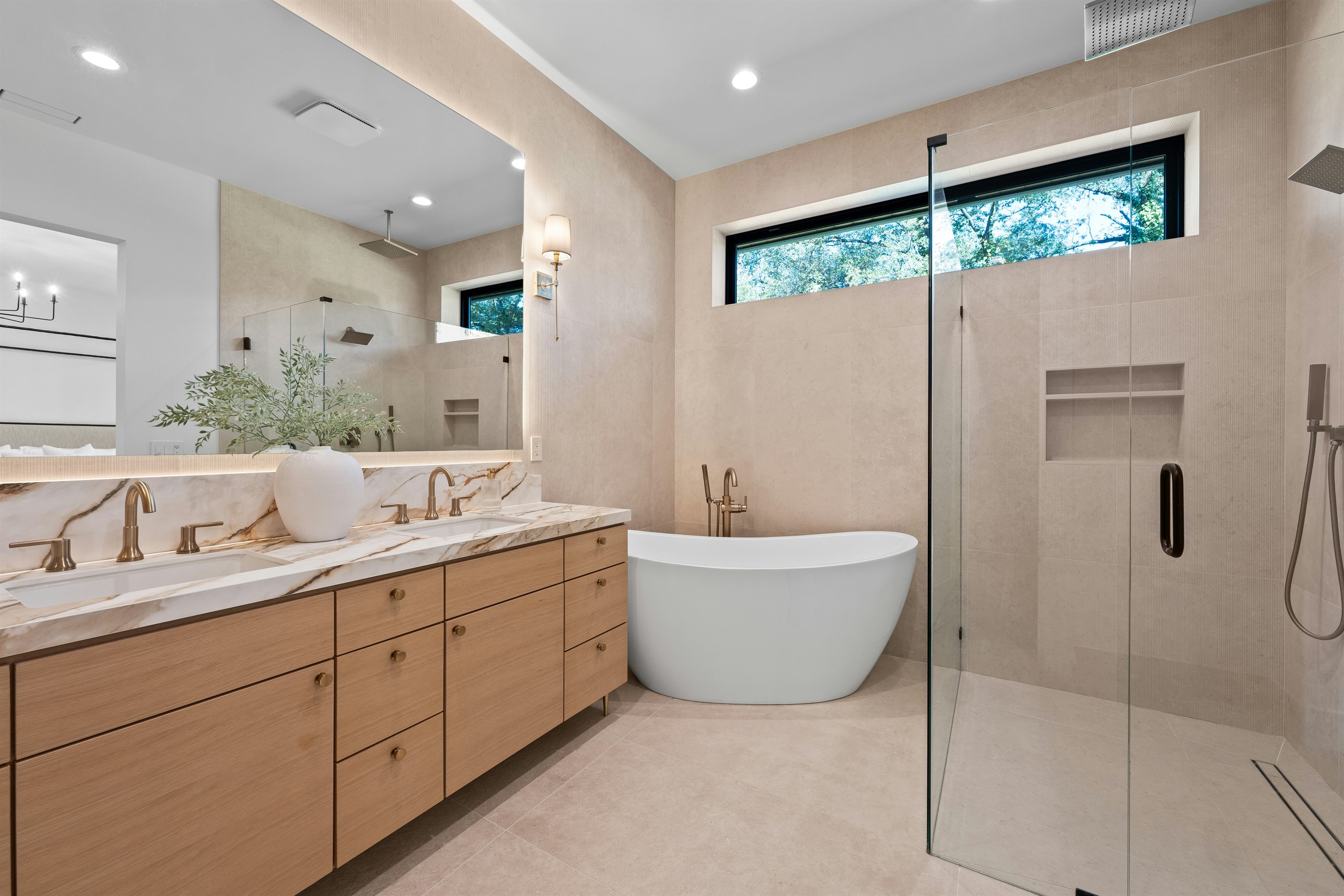 Warm contemporary bathroom with timber vanity, marble surface and freestanding bath
